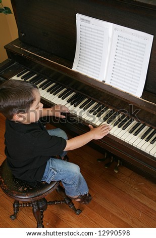 a male youth practicing songs on the piano keys