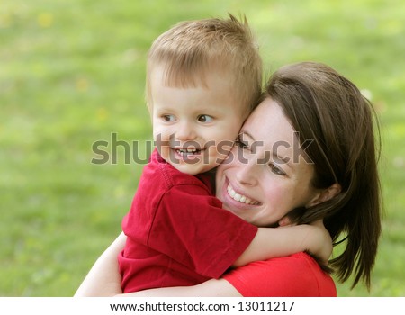 close up portrait headshot of a mother and son smiling and hugging each other looking off camera