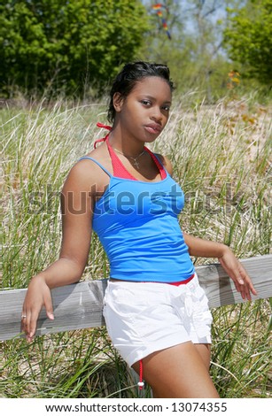 a young African American woman leaning against a wood railing
