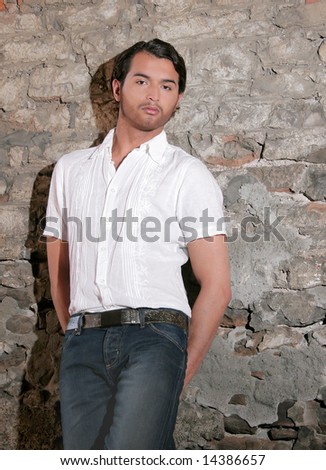 dark haired young guy posing against a wall