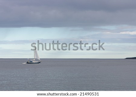 a simple sailboat sailing in the blue ocean during a stormy day