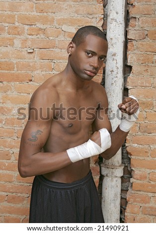 a young black male preparing to fight with taped hands in urban scene
