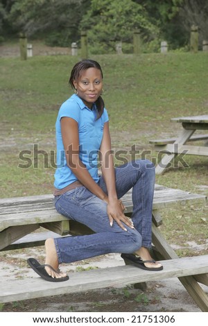 one young African American woman sitting on a picnic table in the park
