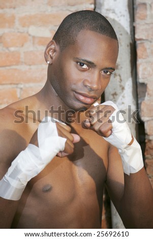 a young black male preparing to fight with taped hands in urban scene
