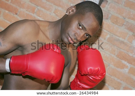 a young black male preparing to fight with gloved hands in urban scene