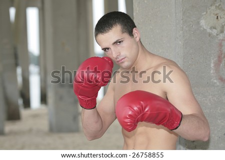 a young topless male boxer with red gloves outdoors