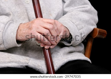 one elderly woman\'s hands holding her cane in her lap