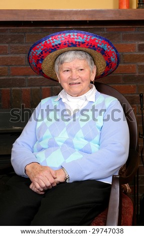 funny elderly lady sitting near a fireplace in a mexican sombrero