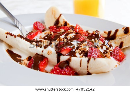 one healthy plate of banana split with yogurt, strawberries and low fat hot fudge topping