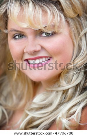 headshot portrait of a blonde young adult woman smiling. gorgeous plus size model closeup. vertical format.