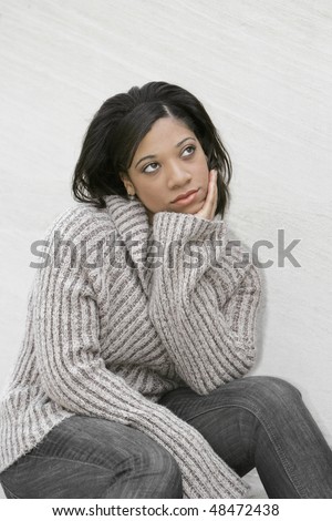 young attractive African American woman thinking outdoors against a light colored wall