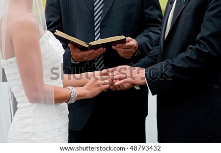 stock photo : bride and groom holding hands during ring exchange part of an 