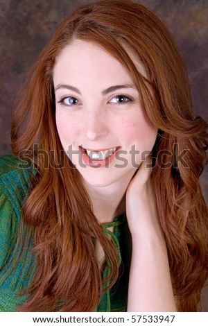 one cute twenties redhead model smiling for a portrait against a brown toned background