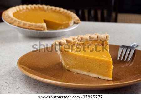 one slice of pumpkin  pie removed from the whole and ready to eat