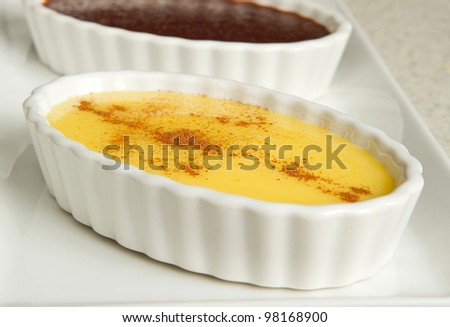 three puddings with chocolate and vanilla in metal tins on a white serving platter