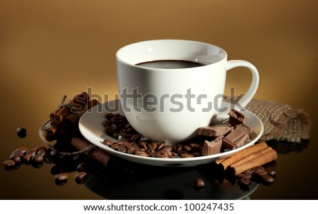 cup of coffee and beans, cinnamon sticks and chocolate on brown background