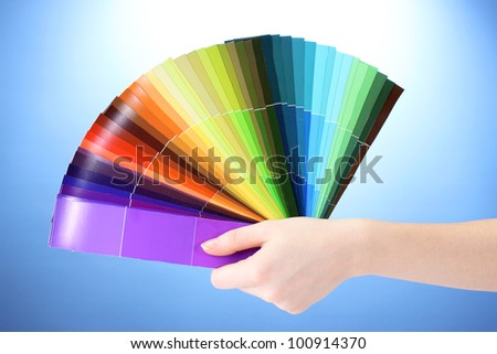 hand holding bright palette of colors on blue background