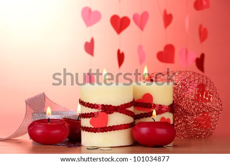 candles for Valentine\'s Day on wooden table on red background
