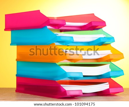 bright paper trays on wooden table on yellow background