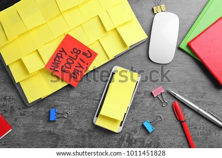 Smartphone and laptop covered in sticky notes. April fool\'s day celebration