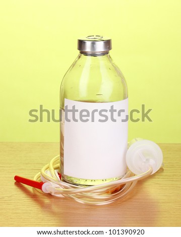 Bottle of intravenous antibiotics and plastic infusion set on wooden table on green background