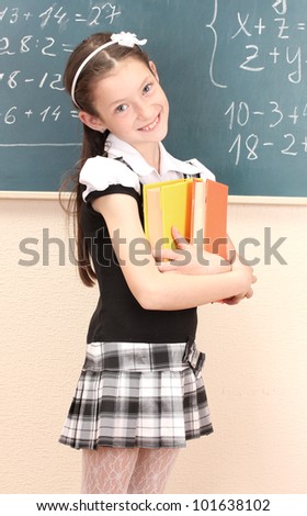 beautiful little girl in school uniform with books in class room