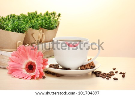 cup of coffee with lipstick mark and gerbera beans, cinnamon sticks on wooden table