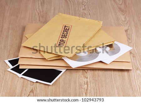 Envelopes with top secret stamp with photo papers and CD disks on wooden background