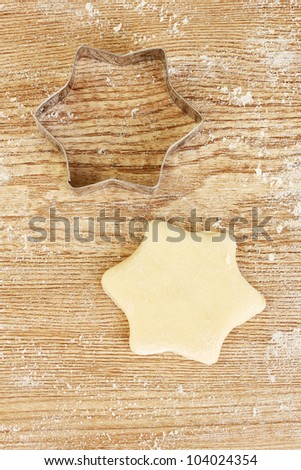 cutter for the dough to the unbaked biscuits on a wooden table close-up