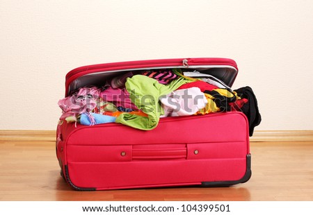 ?losed red suitcase with clothing in the room