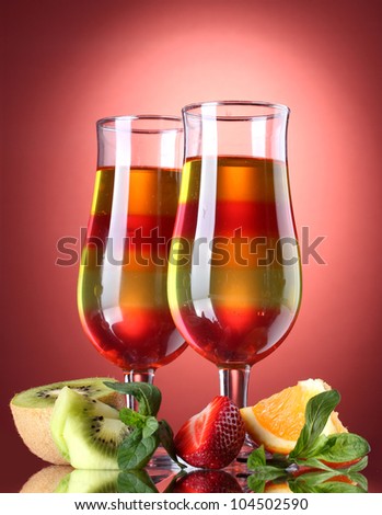 fruit jelly in glasses and fruits on red background