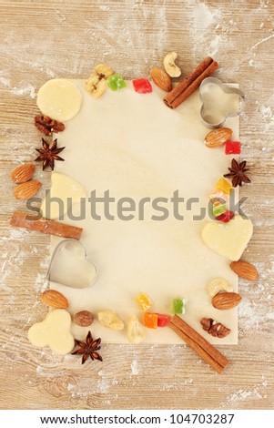Frame made of candied fruit, nuts, unbaked biscuits and molds for cookies on parchment close-up