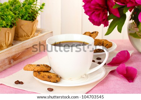 cup of coffee, cookies and flowers on table in cafe