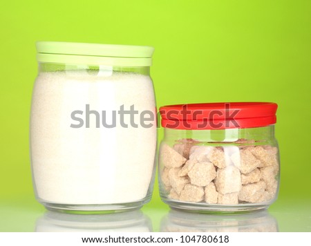 Jars with brown cane sugar lump and white crystal sugar on colorful background