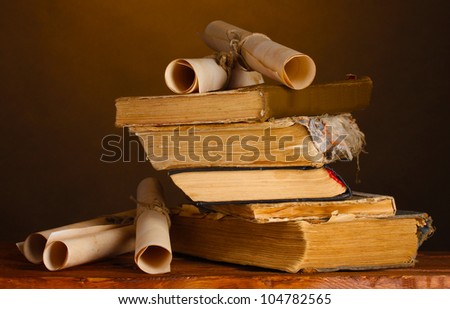 Pile of old books and scroll on brown