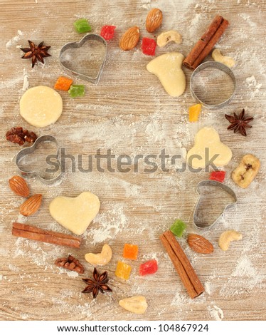 Frame made of candied fruit, nuts, unbaked biscuits and molds for cookies on a wooden table close-up