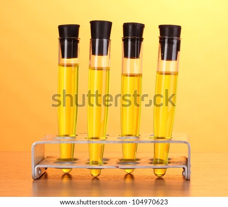 Test-tubes with yellow liquid on wooden table on yellow background