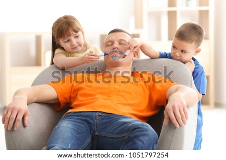 Little children painting their father\'s face while he sleeping. April fool\'s day prank