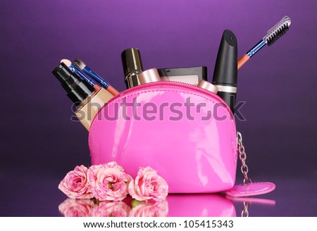 Make up bag with cosmetics and brushes on violet background