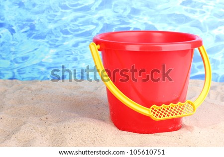 Children\'s bucket on sand on water background