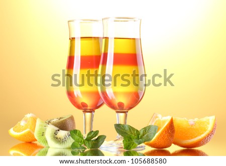 fruit jelly in glasses and fruits on yellow background
