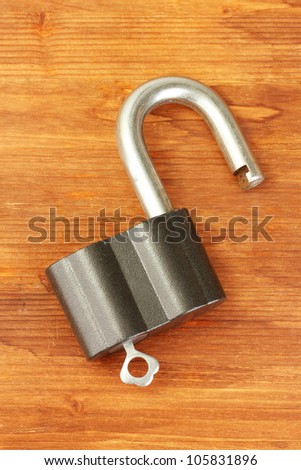 old padlock with key on wooden background close-up