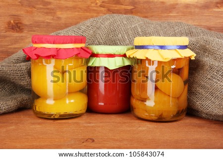 Jars with canned fruit on wooden background close-up