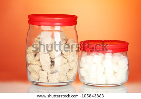 Jars with brown cane sugar lump and white lump sugar isolated on white