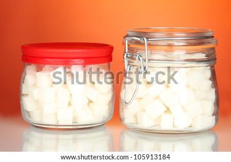 Jar and sugar-bowl with white lump sugar on colorful background