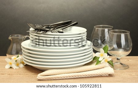 empty clean plates and glasses on wooden table on grey background