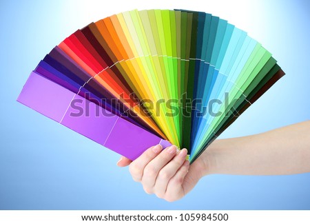 hand holding bright palette of colors on blue background