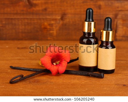 Vanilla pods with essential oil on wooden background close-up