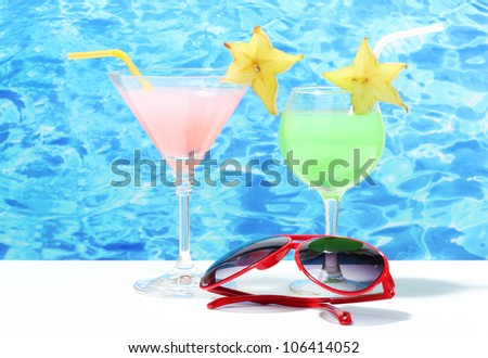 Glasses of cocktails on table on blue sea background
