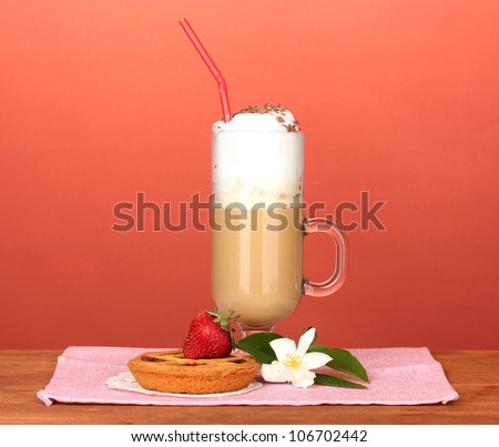 glass of coffee cocktail on colorful napkin with tart and flower on bright background